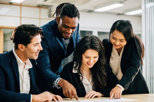 Diverse colleagues, under the leadership of a female boss, engage in a meeting room discussion. They work together, review documents, and brainstorm solutions for global success. Teamwork