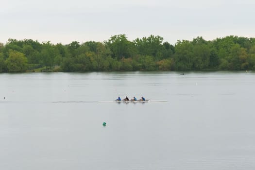 Bordeaux, France - April 26, 2023: A group of people rowing a boat on a serene lake, enjoying a day of outdoor adventure and teamwork.