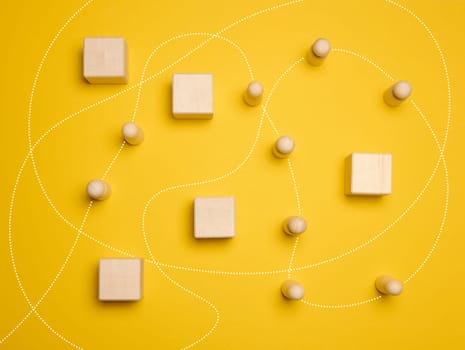 Wooden figures of men and a trajectory between obstacles on a yellow background, top view