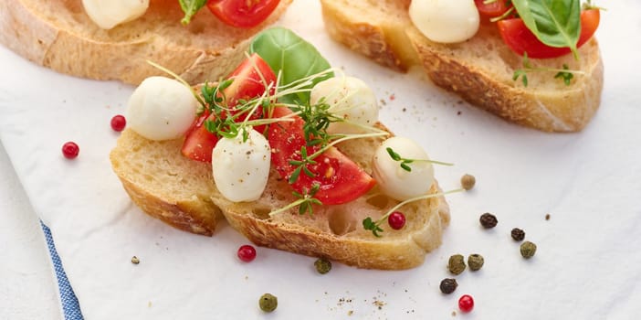 Round mozzarella, cherry tomatoes and microgreens on a piece of white bread, a healthy sandwich, top view