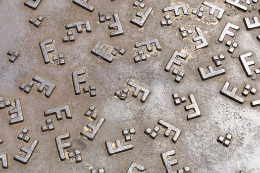A collection of metal letters arranged neatly on a textured metal surface.