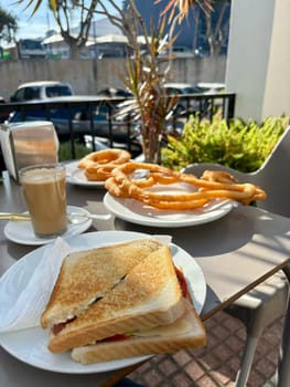 Spanish breakfest - coffee cortado, sandwich and churros in outdoor summer terrace. High quality photo