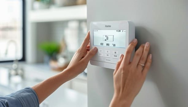 A person is setting a thermostat on a wall, probably in a kitchen or living space, using their finger to adjust it