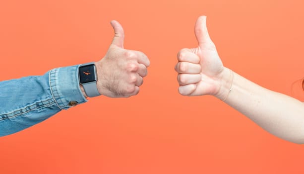 A man and a woman are communicating using hand gestures, approving each other with a thumbsup sign