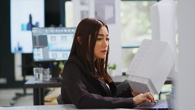 Developer analyzing 3d building model at realty office, examining measurements for the actual construction scale. Engineer calculating industrial lines and elements on laptop blueprint draft.