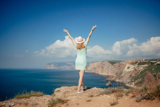 Woman tourist sky sea. Happy traveler woman in hat enjoys vacation raised her hands up.