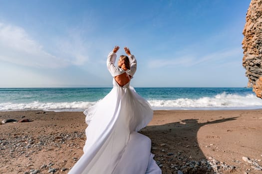 Woman beach white dress flying on Wind. Summer Vacation. A happy woman takes vacation photos to send to friends