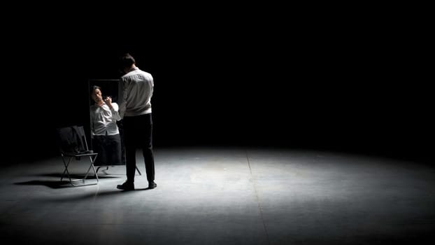 Man applies powder to his face with brush. Stock footage. Man puts powder on face on theater stage. Theatrical production with one man putting powder on face.