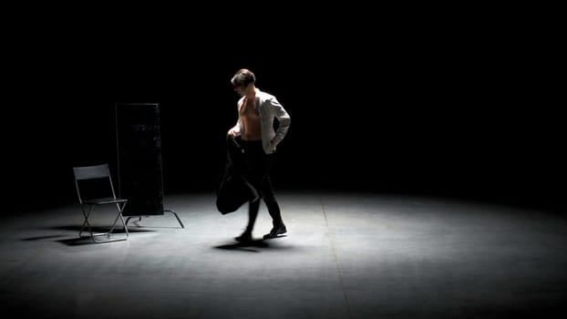 Man in suit alone on theater stage. Stock footage. Single attractive man in suit is playing on stage of theater. Man in suit with mirror is alone on dark theatrical stage.