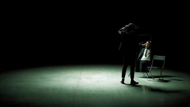 Man combs his hair in front of mirror on stage. Stock footage. Man in suit combs hair in front of mirror. Stage production with one man in suit and mirror.