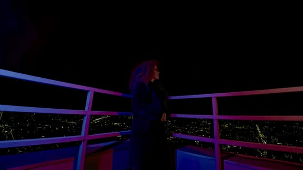 Woman with glasses on roof of building. Media. Fashion woman in coat and glasses stands on roof of high-rise building. Stylish night photo shoot with woman in gloomy image.