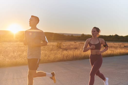 A handsome young couple running together during the early morning hours, with the mesmerizing sunrise casting a warm glow, symbolizing their shared love and vitality.