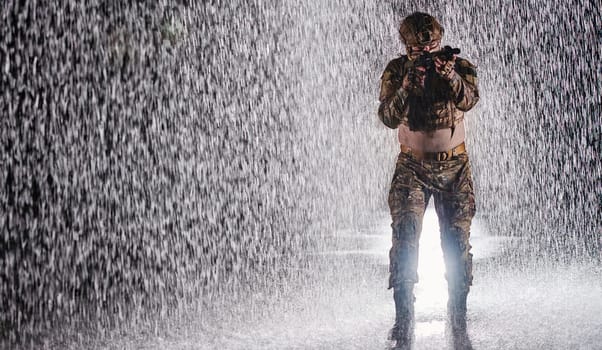 Army soldier in Combat Uniforms with an assault rifle, plate carrier and combat helmet going on a dangerous mission on a rainy night