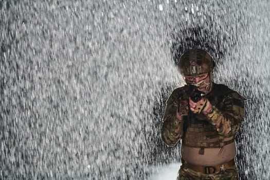 Army soldier in Combat Uniforms with an assault rifle, plate carrier and combat helmet going on a dangerous mission on a rainy night