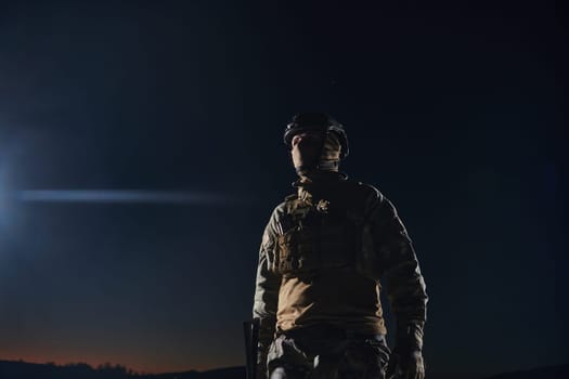 A professional soldier in full military gear striding through the dark night as he embarks on a perilous military mission.