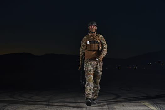 A professional soldier in full military gear striding through the dark night as he embarks on a perilous military mission.