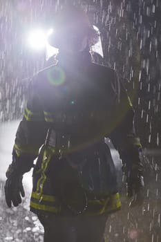 A determined female firefighter in a professional uniform striding through the dangerous, rainy night on a daring rescue mission, showcasing her unwavering bravery and commitment to saving lives