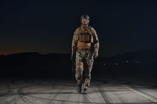 A professional soldier in full military gear striding through the dark night as he embarks on a perilous military mission.