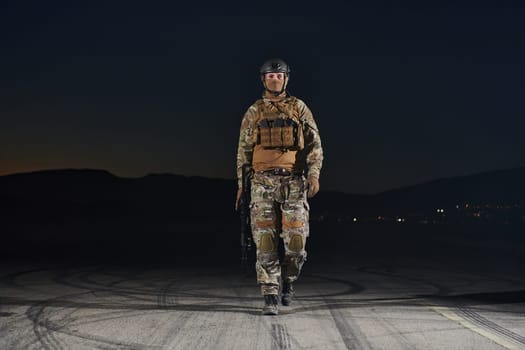 A professional soldier in full military gear striding through the dark night as he embarks on a perilous military mission.