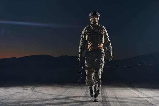 A professional soldier in full military gear striding through the dark night as he embarks on a perilous military mission.