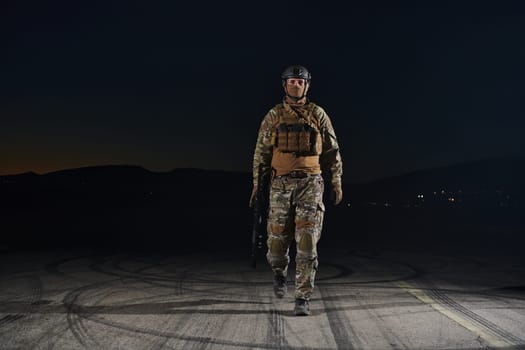 A professional soldier in full military gear striding through the dark night as he embarks on a perilous military mission.