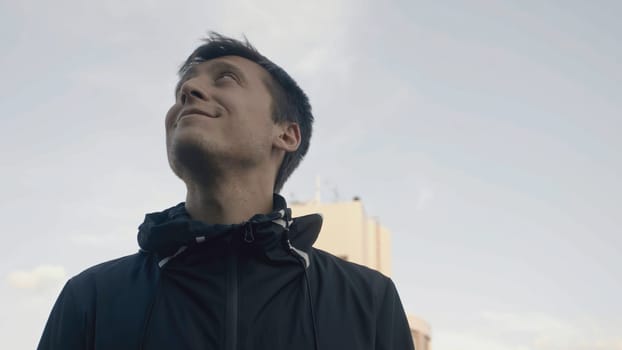 Close-up of man looking at sky with smile. Stock. Man looks up happily and inspiringly. Man looks back up and smiles happily.