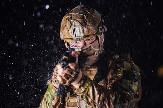 Army soldier in Combat Uniforms with an assault rifle, plate carrier and combat helmet going on a dangerous mission on a rainy night