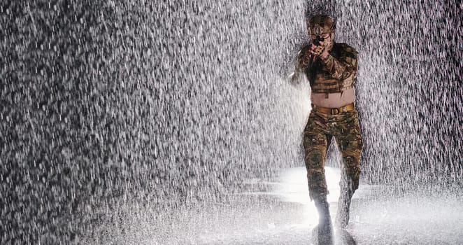 Army soldier in Combat Uniforms with an assault rifle, plate carrier and combat helmet going on a dangerous mission on a rainy night