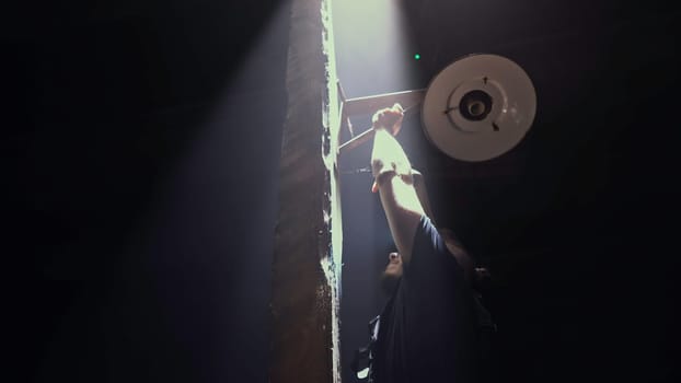 Low angle view of a male worker fixing vintage lantern on a dark background. Media. Man fixing ancient wooden street light