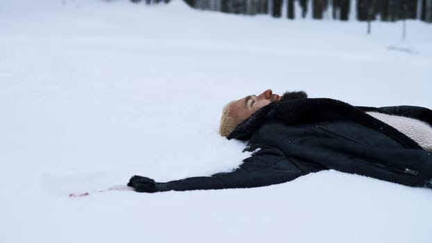 Happy young man in fairytale winter forest lying on snow. Media. Concept of religion and feeling unity with nature