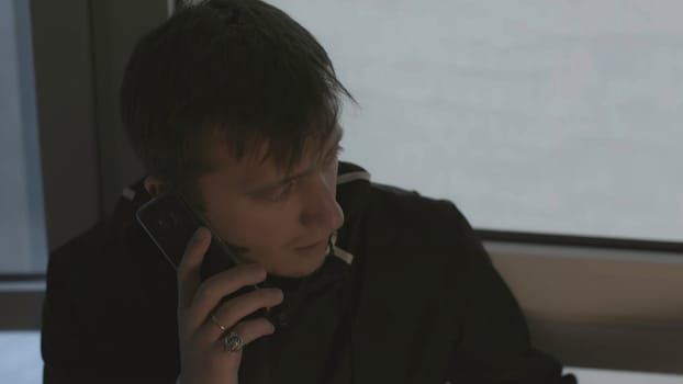 Man is calling excitedly on phone. Stock. Close-up of man calling and talking on phone. Man is making phone call on background of windows.