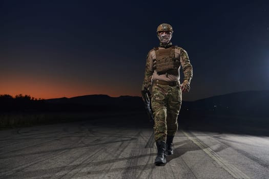 A professional soldier in full military gear striding through the dark night as he embarks on a perilous military mission.