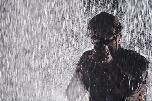 Army soldier in Combat Uniforms with an assault rifle, plate carrier and combat helmet going on a dangerous mission on a rainy night