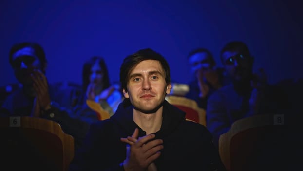 Young man is watching concert and applauding. Media. Young man is watching theater concert. Performance of play with applauding audience.