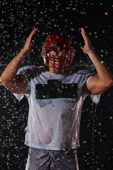 American Football Field: Lonely Athlete Warrior Standing on a Field Holds his Helmet and Ready to Play. Player Preparing to Run, Attack and Score Touchdown. Rainy Night with Dramatic Fog, Blue Light.