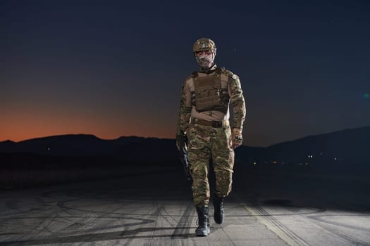 A professional soldier in full military gear striding through the dark night as he embarks on a perilous military mission.