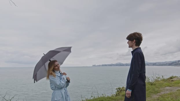 Young couple dating by the ocean shore and communicating. Stock clip. Man and woman spend time outdoors on a cold windy day