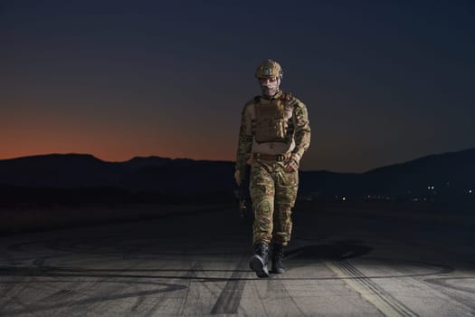 A professional soldier in full military gear striding through the dark night as he embarks on a perilous military mission.