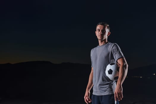 Portrait of a young handsome soccer player man on a street playing with a football ball