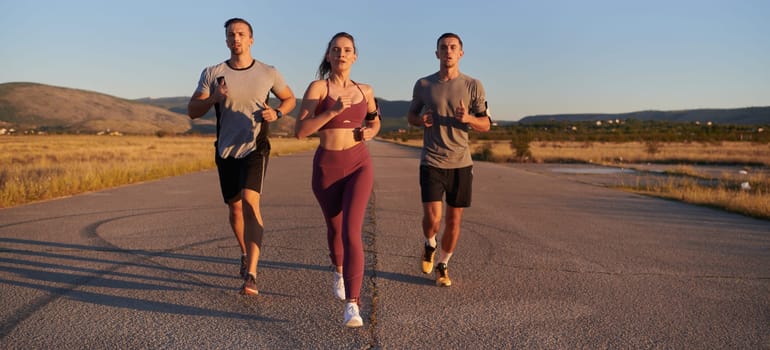 A group of young athletes running together in the early morning light of the sunrise, showcasing their collective energy, determination, and unity .