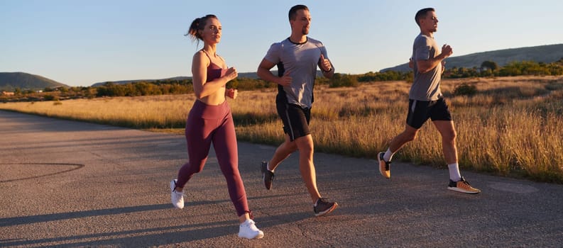 A group of young athletes running together in the early morning light of the sunrise, showcasing their collective energy, determination, and unity .