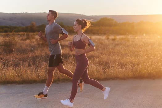 A handsome young couple running together during the early morning hours, with the mesmerizing sunrise casting a warm glow, symbolizing their shared love and vitality.