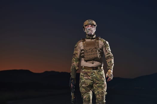 A professional soldier in full military gear striding through the dark night as he embarks on a perilous military mission.