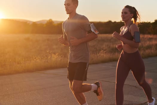 A handsome young couple running together during the early morning hours, with the mesmerizing sunrise casting a warm glow, symbolizing their shared love and vitality.