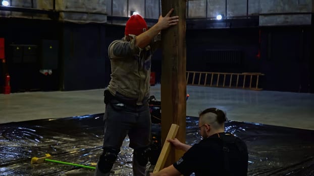 Assembly of wooden stage construction by young builders. Media. Men workers using logs for the decorations of the concert