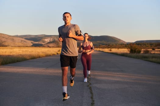 A handsome young couple running together during the early morning hours, with the mesmerizing sunrise casting a warm glow, symbolizing their shared love and vitality.