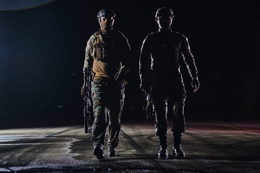 Two professional soldiers marching through the dark of night on a dangerous mission, epitomizing their unwavering bravery, unwavering teamwork, and the high-stakes intensity of their specialized training as they prepare to confront unknown perils in the name of duty and sacrifice