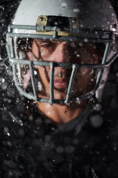 American Football Field: Lonely Athlete Warrior Standing on a Field Holds his Helmet and Ready to Play. Player Preparing to Run, Attack and Score Touchdown. Rainy Night with Dramatic Fog, Blue Light.