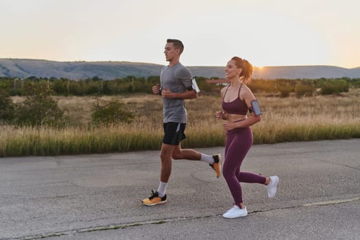 A handsome young couple running together during the early morning hours, with the mesmerizing sunrise casting a warm glow, symbolizing their shared love and vitality.