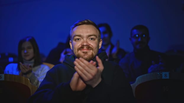 Young man is watching theatrical performance. Media. Man is watching theatrical performance in place. Spectator illuminated by spotlight at theatrical performance.